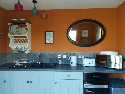 Modern kitchen featuring orange walls, a mirror, and various kitchen appliances.